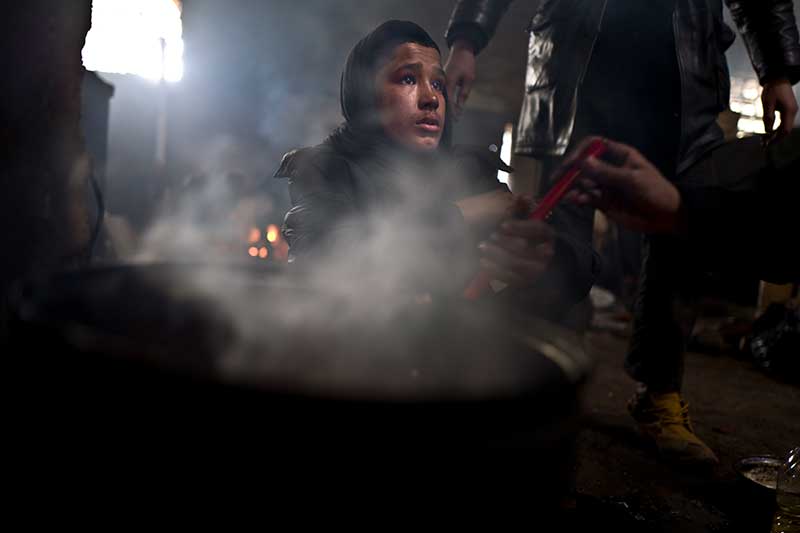 12-year-old unaccompanied refugeeminor Liaqat, from Khogyani, Afghanistan, cooks on a fire in an abandoned warehouse where he and other refugees took refuge in Belgrade, Serbia, February 2017.