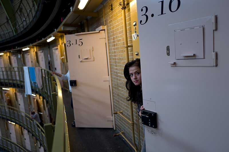 19-year-old Afghan refugee Shazia Lutfi peeks through the door of her room at the former prison of De Koepel in Haarlem, Netherlands, May 2016.